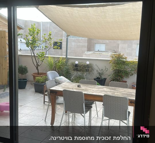 דלת הזזה מזכוכית המשקיפה אל מרפסת פתוחה עם פינת ישיבה
